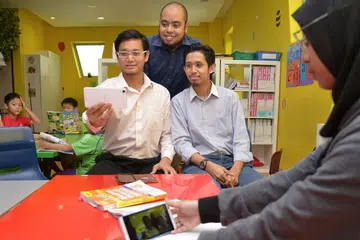 TEROKA DIGITAL: (Dari kanan) Encik Muhammad Mohamed Rahim, Encik Salihin Mohamed Rahim dan Encik Muhammad Taufik Yahya (berdiri) merancang meluaskan aplikasi mereka ke pasaran serantau. Buat masa ini, aplikasi itu sudah menarik perhatian pengguna dari Indonesia. - Foto fail