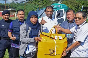 Setiausaha Suruhanjaya Pilihan Raya (SPR) Malaysia, Datuk Ikmalrudin Ishak (kanan) menyerahkan peti undi kepada Ketua Tempat Mengundi, Wan Nazaliza Wan Ismail (tiga dari kiri) untuk Pilihan Raya Kecil (PRK) Dewan Undangan Negeri (DUN) Nenggiri di Kelantan, pada 17 Ogos.