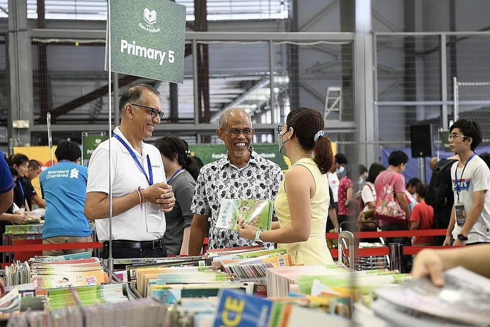 BERBAKTI SAMBIL SELAMATKAN ALAM SEKITAR: Encik Masagos Zulkifli (tengah) dan Ketua Pegawai Eksekutif Kumpulan FairPrice Group, Encik Vipul Chawla (kiri), bercakap dengan salah seorang ibu daripada 25,000 pelajar benefisiari yang diberi keutamaan untuk mengumpul buku teks mereka. - Foto FAIRPRICE GROUP
