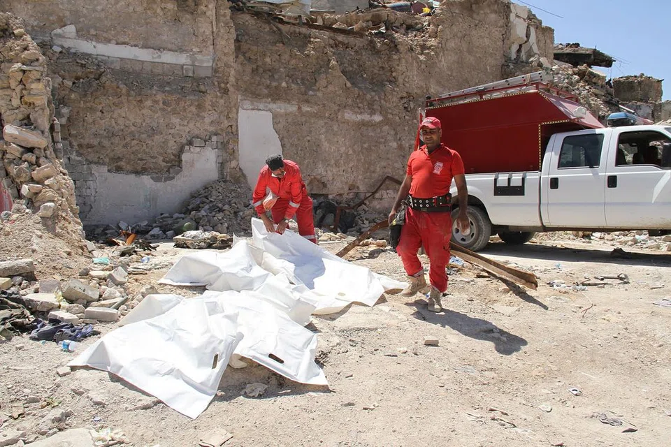 PEKERJAAN GERUN: Anggota pasukan pertahanan awam menutup mayat yang dikeluarkan dari runtuhan di Mosul. Mereka menghadapi ancaman maut daripada tali pinggang bunuh diri militan dan bom yang belum meletup serta penyakit. - Foto AFP 