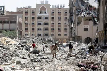 Penduduk Palestin memeriksa puing-puing bangunan yang runtuh di Bandar Hamad ekoran serangan udara Israel ke atas wilayah Khan Younis pada 24 Ogos.