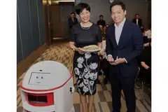 KEMUDAHAN CANGGIH: Cik Indranee mendapatkan makanan yang dihantar robot di Maxwell Chambers. Di sebelah beliau ialah Encik Franklin Tang, CEO Habitap. - Foto KEMENTERIAN UNDANG-UNDANG