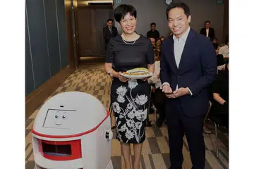 KEMUDAHAN CANGGIH: Cik Indranee mendapatkan makanan yang dihantar robot di Maxwell Chambers. Di sebelah beliau ialah Encik Franklin Tang, CEO Habitap. - Foto KEMENTERIAN UNDANG-UNDANG