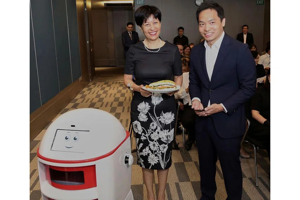 KEMUDAHAN CANGGIH: Cik Indranee mendapatkan makanan yang dihantar robot di Maxwell Chambers. Di sebelah beliau ialah Encik Franklin Tang, CEO Habitap. - Foto KEMENTERIAN UNDANG-UNDANG