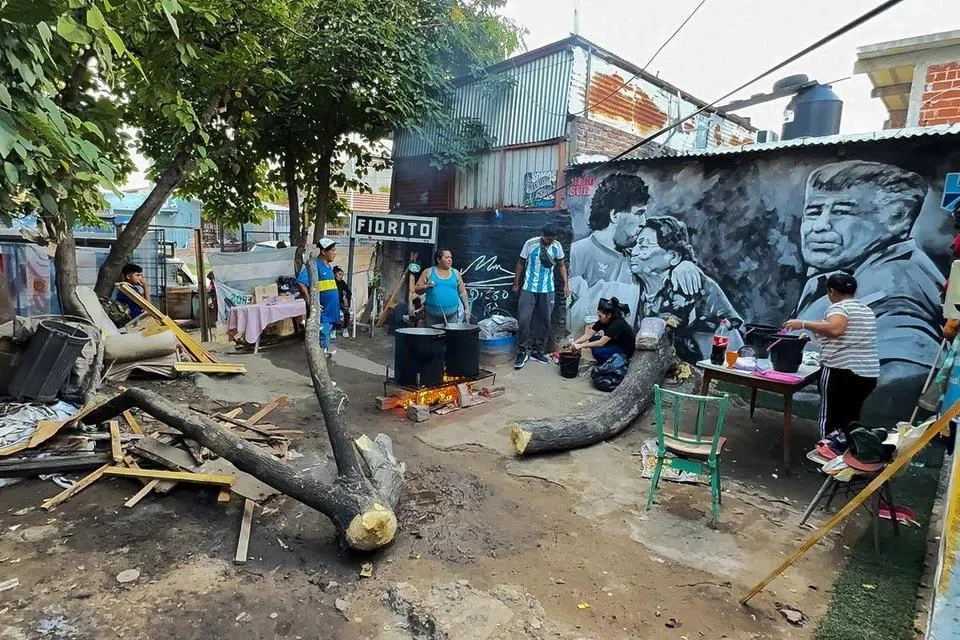 Beberapa sukarelawan memasak buat penduduk di kawasan kejiranan miskin, Villa Fiorito, di sebuah dapur umum di rumah kelahiran legenda bola sepak, Diego Maradona, di pinggir bandar Buenos Aires, Argentina, pada 26 Mac.