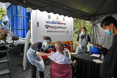MEMUDAHKAN RAKYAT: Seorang kakitangan perubatan memberikan satu dos suntikan vaksin Covid-19 Sinovac ke atas seorang lelaki warga tua di luar klinik vaksinasi bergerak di Kuala Lumpur pada 21 Jun lalu. - Foto AFP
