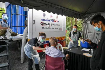 MEMUDAHKAN RAKYAT: Seorang kakitangan perubatan memberikan satu dos suntikan vaksin Covid-19 Sinovac ke atas seorang lelaki warga tua di luar klinik vaksinasi bergerak di Kuala Lumpur pada 21 Jun lalu. - Foto AFP