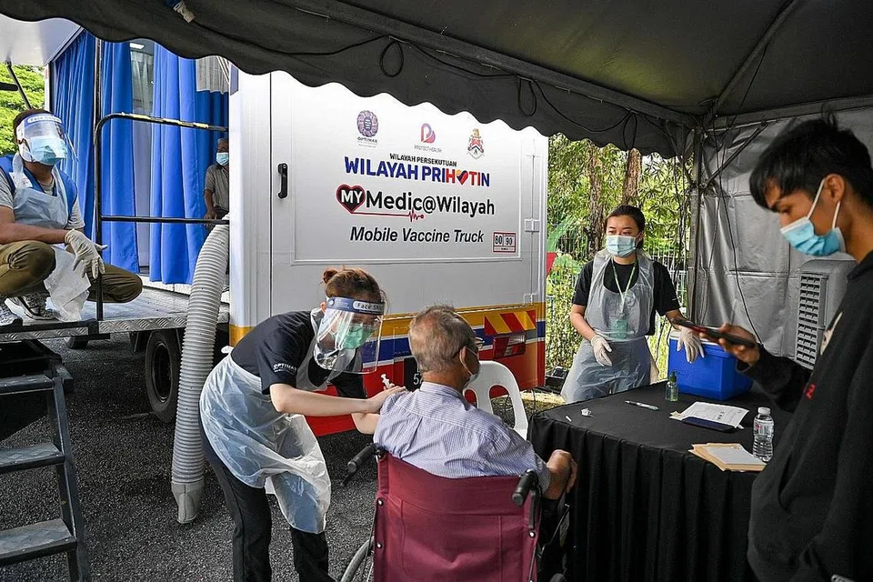 MEMUDAHKAN RAKYAT: Seorang kakitangan perubatan memberikan satu dos suntikan vaksin Covid-19 Sinovac ke atas seorang lelaki warga tua di luar klinik vaksinasi bergerak di Kuala Lumpur pada 21 Jun lalu. - Foto AFP