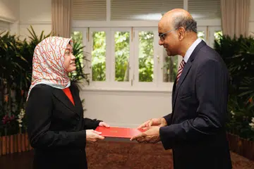 Ketua Pegawai Eksekutif (CEO) Mendaki, Cik Zuraidah Abdullah (kiri), menerima watikah pelantikan daripada Presiden Tharman Shanmugaratnam. Beliau dilantik sebagai Duta Singapura ke Kesultanan Oman (Bukan Pemastautin).
