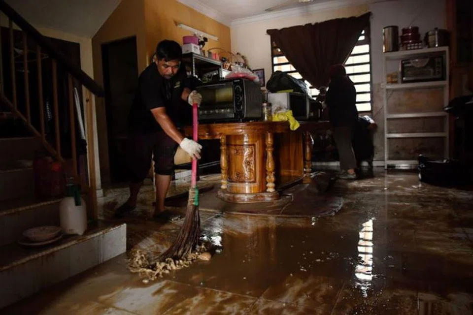 Penduduk Taman Arena Kepayang Putra, Ipoh, Perak, membersihkan rumah mereka yang disaluti lumpur selepas banjir semakin surut.