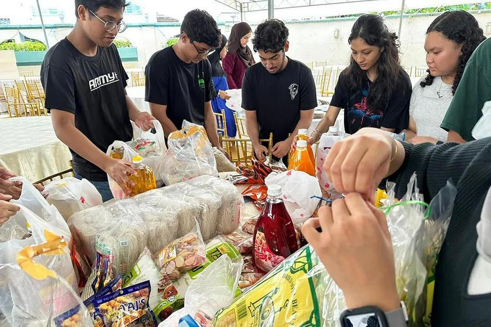 HULUR SUMBANGAN: Sukarelawan dan anggota Al Wehdah menyingsing lengan untuk mengagihkan barangan runcit kepada keluarga yang kurang bernasib baik sempena acara Maidahturrahman. - Foto AL WEHDAH