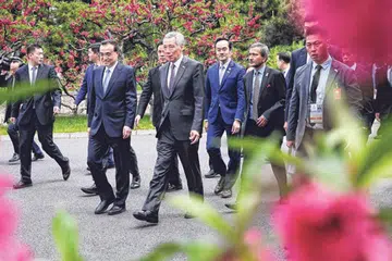 BERAMAH MESRA: Encik Lee (depan, tengah) bersama Perdana Menteri China Li Keqiang berjalan ke tempat menjamu selera bersama rombongan masing-masing di Diaoyu Tai, Beijing, pada 29 April lalu.