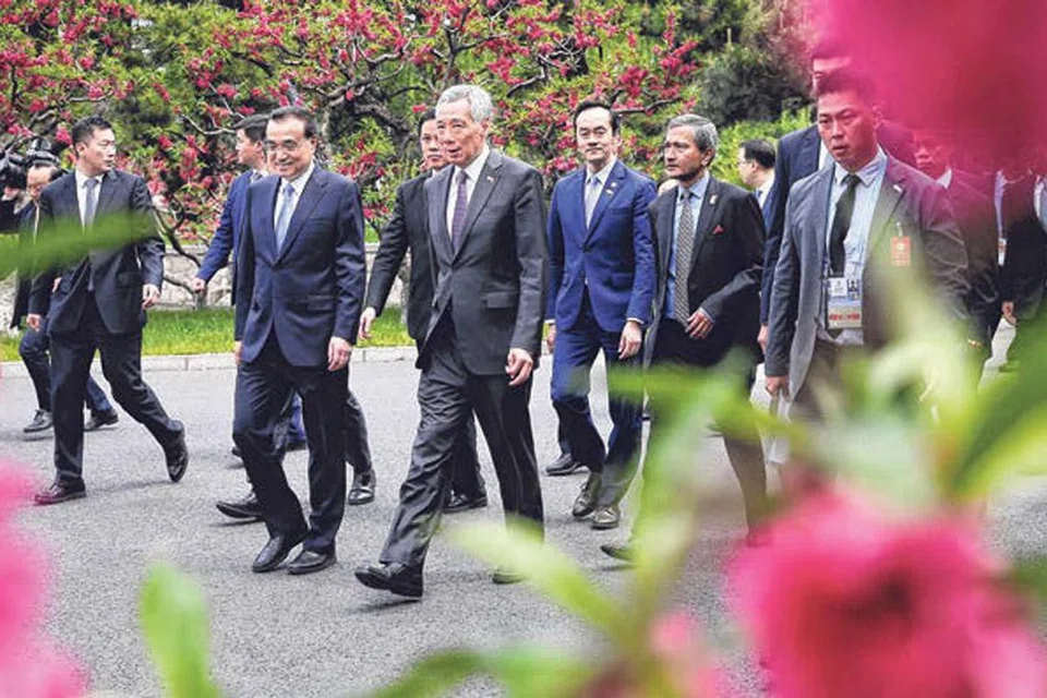 BERAMAH MESRA: Encik Lee (depan, tengah) bersama Perdana Menteri China Li Keqiang berjalan ke tempat menjamu selera bersama rombongan masing-masing di Diaoyu Tai, Beijing, pada 29 April lalu.