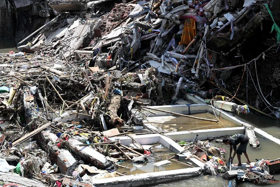 Seorang lelaki (kanan) berjalan di atas runtuhan bangunan yang roboh selepas banjir di Denpasar, pulau peranginan Bali, Indonesia pada 12 September 2025. Hujan lebat sejak malam 9 September mencetuskan banjir dan tanah runtuh di tujuh daerah di seluruh Bali, menurut jurucakap Agensi Pengurusan Bencana Negara (BNPB), Abdul Muhari dalam satu kenyataan.