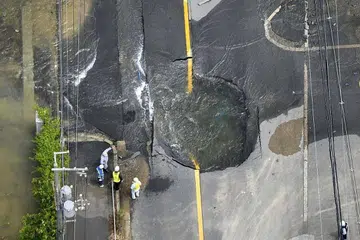 JALAN RAYA ROSAK: Air mengalir keluar dari jalan raya yang rosak akibat gempa bumi di Takatsuki, Osaka, pada 18 Jun 2018. 