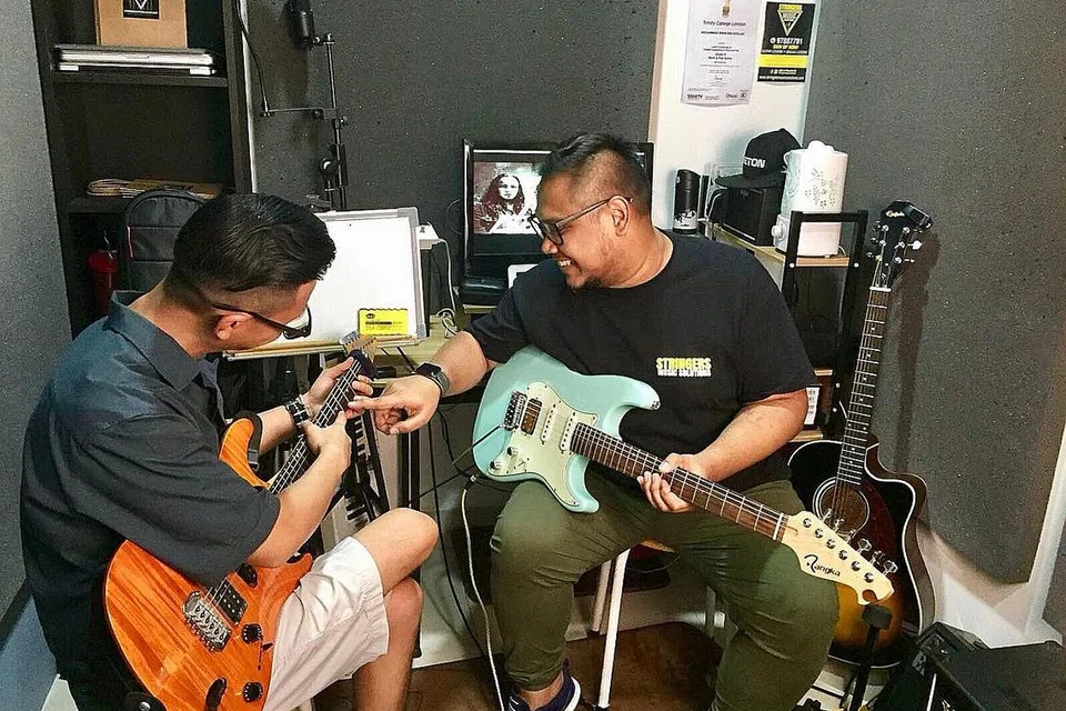 KONGSI ILMU: Mohammad Irwin Roslan (kanan) membuka sekolah muziknya sendiri, Stringers Music Solution, di Suites @ Bukit Timah Mei lalu dengan harapan dapat menggalak lebih ramai anak Melayu tampil mendapatkan asas bermain gitar dan ukulele yang kukuh. - FOTO ADNAN OTHMAN / ALL MUSIC X'CESS