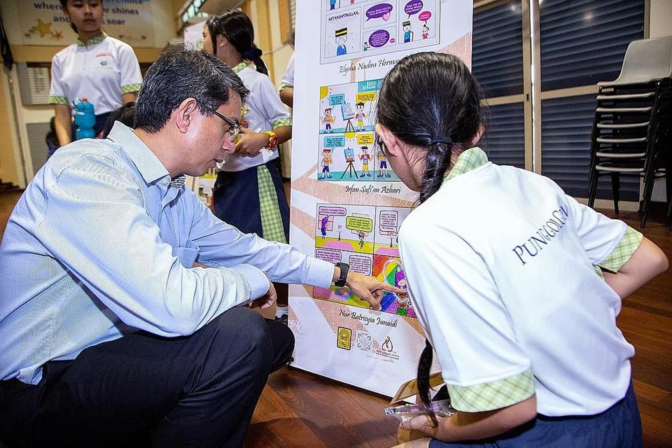 PUPUK DAYA CIPTA: Profesor Madya Muhammad Faishal Ibrahim (kiri) meninjau karya murid dalam 'Peraduan Kartunis Cilik Antara Sekolah' anjuran Sekolah Rendah White Sands sempena Bulan Bahasa, baru-baru ini. - Foto BH oleh ZALEHA ABDUL KADER