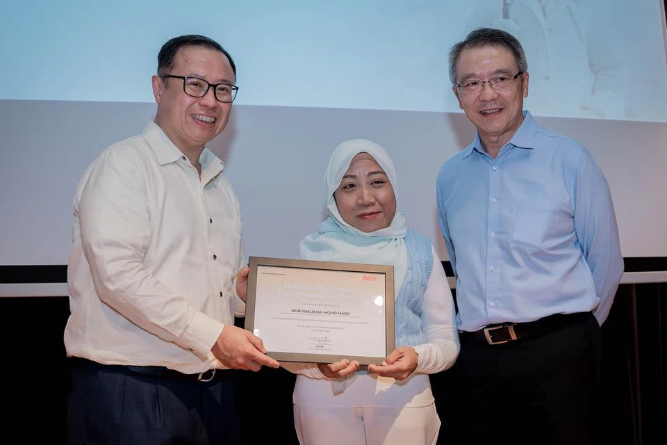 Cik Nur Hailikha Mohd Haer diberikan Anugerah Penjaga Berdedikasi sempena acara Yayasan Buah Pinggang Kebangsaan (NKF) bagi memperingati 55 tahun Memberi Kehidupan & Harapan, disampaikan oleh Pengerusi NKF, Encik Arthur Lang (kiri) dan Encik Tim Oei, Ketua Pegawai Eksekutif NKF.