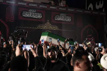 Orang ramai menggunakan telefon bimbit untuk merakam ketibaan keranda bekas Pemimpin Tertinggi Iran, Ali Khamenei, di Lapangan Terbang Antarabangsa Najaf, Iraq, pada 7 Julai 2026. Jenazah Khamenei diterbangkan ke bandar suci Najaf sebagai sebahagian daripada siri upacara penghormatan dan perarakan pengebumian di bandar-bandar suci Syiah yang menempatkan makam paling dihormati oleh umat Islam Syiah.