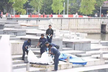 PENEMUAN MAYAT: Anggota polis mengangkat sekujur mayat yang ditemui di Sungai Singapura pagi tadi. - Foto THE STRAITS TIMES