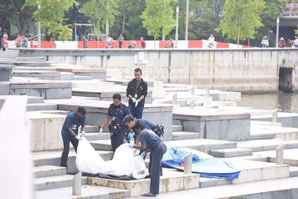 PENEMUAN MAYAT: Anggota polis mengangkat sekujur mayat yang ditemui di Sungai Singapura pagi tadi. - Foto THE STRAITS TIMES