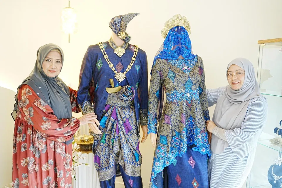 Cik Masturah Abdullah (kiri) dan menantunya, Cik Siti Aisha Salim, masih mempertahankan pakaian pengantin tradisional di samping gaun yang lebih modern.