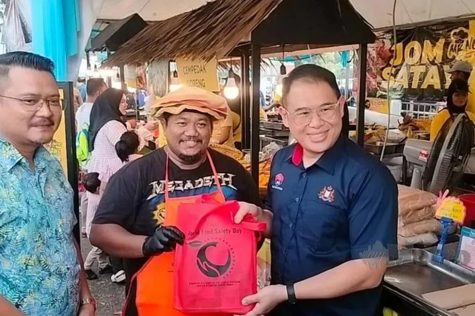 Pengerusi Jawatankuasa Kesihatan dan Alam Sekitar Johor, Encik Ling Tian Soon (kanan), menyerahkan apron dan bahan pendidikan kesihatan kepada peniaga semasa meninjau bazar Ramadan Angsana Mall, Johor Bahru, pada 6 Mac. 