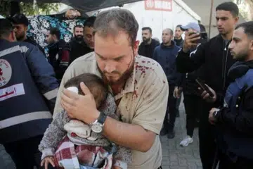 Seorang lelaki Palestin mendukung seorang kanak-kanak yang cedera di sebuah hospital, selepas serangan Israel ke atas sebuah sekolah yang menempatkan penduduk yang dipindahkan di Bandar Gaza. 