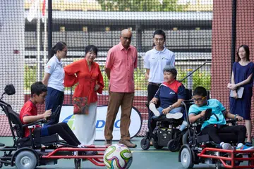 Presiden Tharman Shanmugaratnam (kemeja merah jambu) dan isteri, Cik Jane Ittogi Shanmugaratnam (di sebelahnya), menyaksikan perlawanan Powerchair Football semasa majlis pelancaran Cabaran Presiden di Pusat Sukan Delta ActiveSG pada 4 September. Bersama mereka ialah Ilyas Ardhany Faizal (kiri), penerima manfaat Majlis Sukan bagi Orang Cacat Singapura (SDSC) dan penerima Geran Cabaran Presiden 2024.