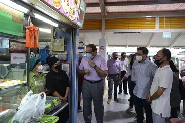 TANYA PERKEMBANGAN DIGITAL: Encik Iswaran (tiga dari kiri) bertanya pegerai di pusat penjaja dan pasar di Blok 210 Toa Payoh Lorong 8 tentang perkembangan penggunaan e-bayaran kod SG QR di gerai makan mereka. - Foto BH oleh TIMOTHY DAVID