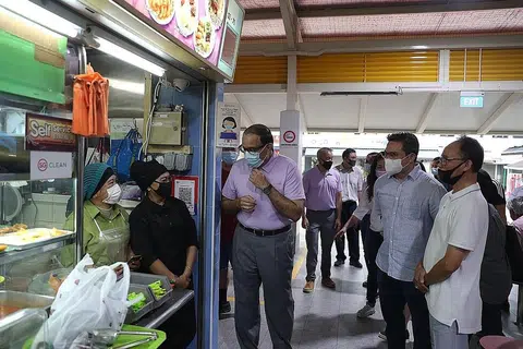 TANYA PERKEMBANGAN DIGITAL: Encik Iswaran (tiga dari kiri) bertanya pegerai di pusat penjaja dan pasar di Blok 210 Toa Payoh Lorong 8 tentang perkembangan penggunaan e-bayaran kod SG QR di gerai makan mereka. - Foto BH oleh TIMOTHY DAVID