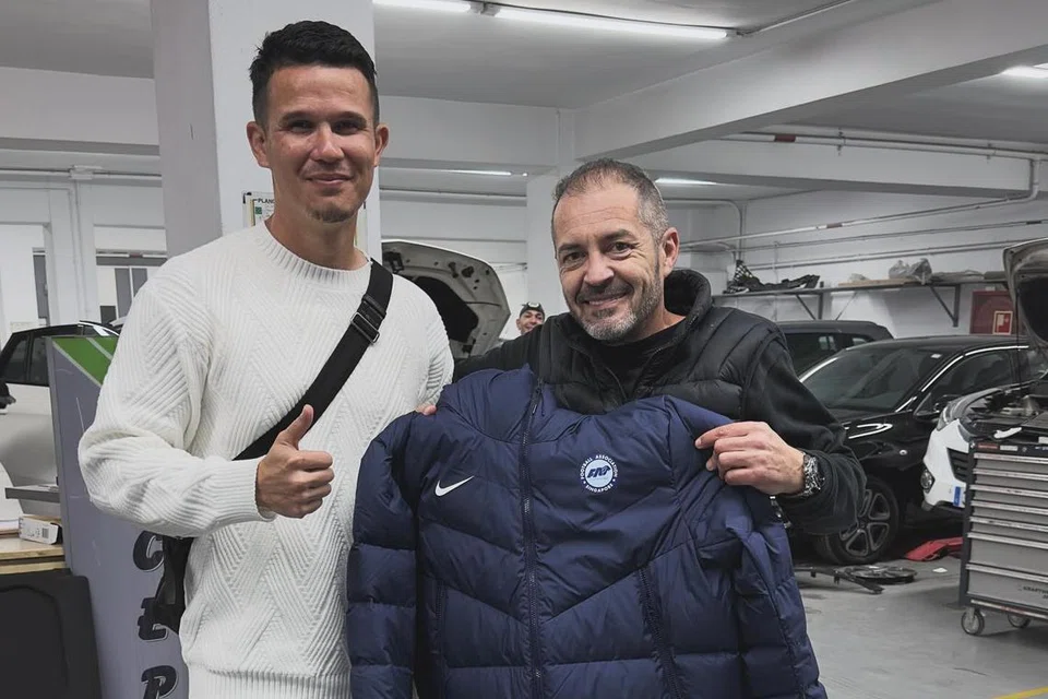 TANDA PENGHARGAAN: Encik Baihakki (kiri) menghadiahkan jaket pasukan negara kepada ‘Javier’, lelaki yang bantu membaiki tayar kereta sewa beliau yang pancit pada 4 Disember setelah dipercayai hampir jadi mangsa perompak.