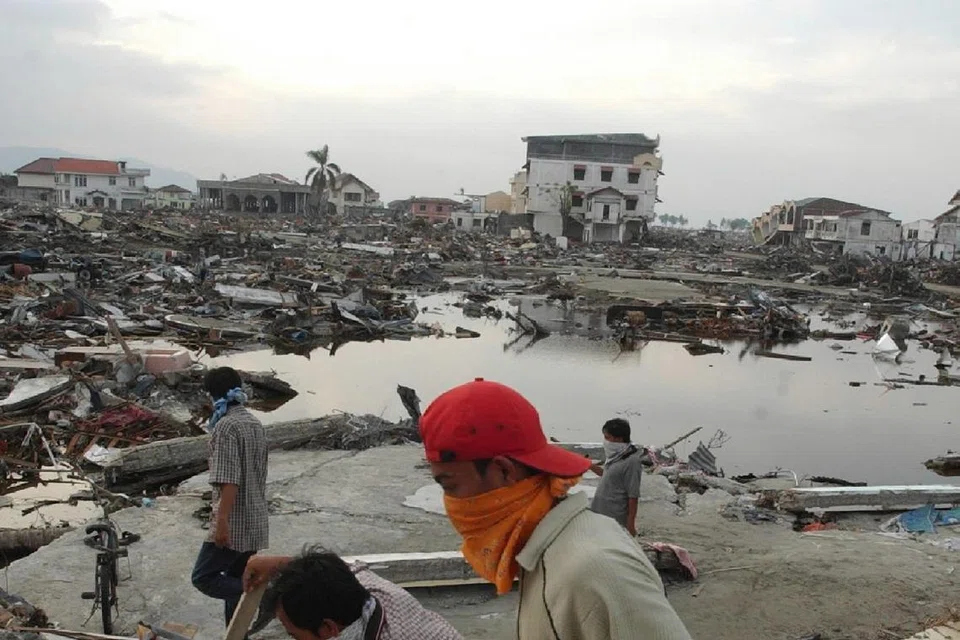 Penduduk Aceh melangkah perlahan melalui sebuah bandar yang musnah, sekitar empat kilometer dari pantai. Jalan dipenuhi mayat, serpihan runtuhan bangunan, bot-bot nelayan serta sisa lain yang dihanyutkan ombak ke darat.