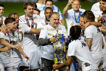 DIJANGKA SAMBUNG KONTRAK: Penguarus Marcelo Bielsa (angkat piala) merai bersama pemain Leeds kejayaan mereka menjuarai liga Championship dan dinaikkan ke EPL bulan lalu. Beliau dijangka menyambut kontraknya. - Reuters