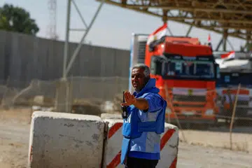 TRAK BANTUAN KEMANUSIAAN: Seorang pekerja PBB beri isyarat supaya trak bantuan masuk Lintasan Rafah untuk ke Jaluran Gaza.