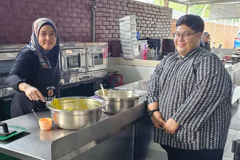 DIBUAT SEGAR SETIAP HARI: Penulis (kanan) ke kilang Kek Lapis Warisan dengan para pelancong boleh melihat sendiri bagaimana juadah itu dihasilkan. 