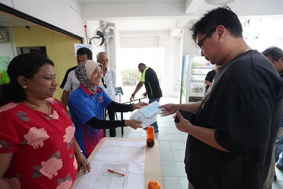Seorang penduduk mengambil pelitup muka di kaunter pengambilan di Pusat RC di Blok 47, Telok Blangah Drive.