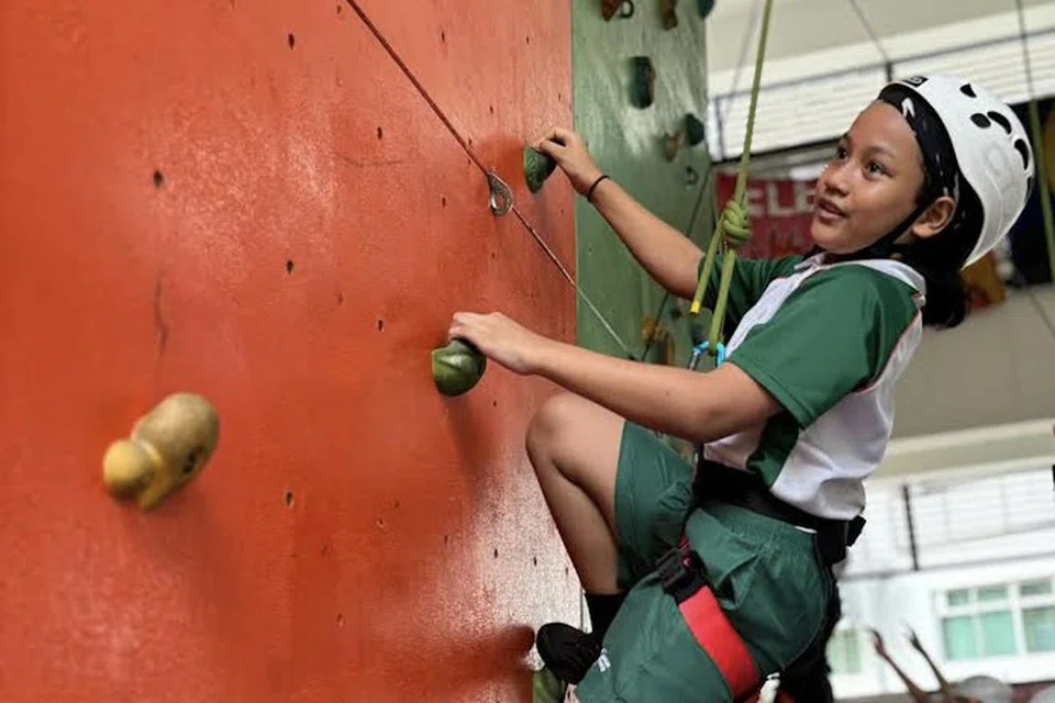 Pelajar Sekolah Rendah Greendale memanjat dinding panjat tebing yang terletak di Sekolah Menengah Greendale untuk latihan Kepimpinan Pendidikan Di Luar.