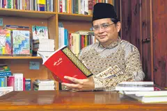 GUNA KAEDAH ESTETIK: Pengkaji tulisan Jawi Dr Hirman Mohamed Khamis menyarankan memancing minat anak muda terhadap bahasa warisan itu menggunakan kaedah estetik. Contohnya, kita boleh menyepadukan unsur warna dan lukisan persis rekaan grafik atau grafiti (contoh lukisan terakam pada bahagian kiri gambar utama, dalam rak-rak buku). - Foto BM oleh YONG LI XUAN