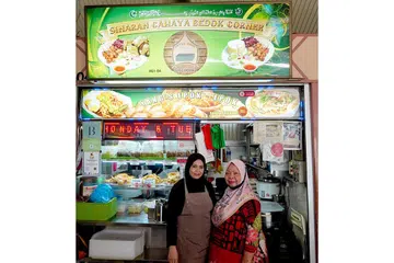 EPOK-EPOK: Selepas Cik Yang Hassan (kanan) buka gerainya semula pada 2015, beliau dapati ramai penjaja Melayu di Pusat Penjaja Bedok Corner menjual jamuan nasi seperti nasi padang dan nasi ambeng. Kini, anaknya Cik Rahimah Sinwan (kiri) akan teruskan resipi moyang mereka dalam membuat perniagaan epok-epok. - Foto BH oleh SYED MUHAMMAD FIRDAUS