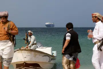KAWALAN DITINGKAT DI LAUT MERAH: Fota fail menunjukkan lelaki bersenjata berdiri di pantai ketika kapal komersial Galaxy Leader, yang dirampas oleh Houthi Yaman bulan lalu, berlabuh di luar pantai al-Salif, Yaman, 5 Disember 2023.