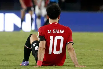 TERPAKSA DIKELUARKAN: Pemain sayap Mesir Mohamed Salah terduduk di padang semasa perlawanan menentang Ghana, sebelum terpaksa dikeluarkan. 