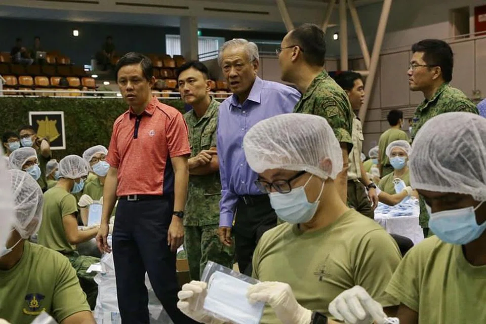 BERSAMA ATASI WABAK: Menteri Pertahanan Dr Ng Eng Hen (berbaju biru) dan Menteri Perdagangan dan Perusahaan Chan Chun Sing (berbaju merah) meninjau pembungkusan pelitup oleh anggota Angkatan Bersenjata Singapura (SAF) pada 31 Januari 2020.