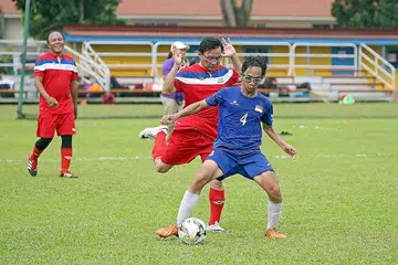 PERLAWANAN PERSAHABATAN: Pemain pasukan CP, Shafiq Ariff (jersi biru), mengawal bola daripada dicuri Anggota Parlimen (AP) Bishan-Toa Payoh GRC, Encik Chong Kee Hiong. Memerhatikan mereka ialah AP Aljunied GRC, Encik Faizal Manap. - Foto THE STRAITS TIMES