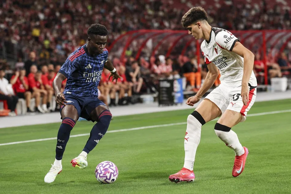 Penyokong Singapura, dapat menyaksikan kelicikan pemain sayap Arsenal, Bukayo Saka (kiri), semasa menentang AC Milan dalam perlawanan persahabatan mereka pada 23 Julai. Perlawanan tersebut diadakan di Stadium Negara, sebahagian daripada Festival Bola Sepak Singapura.