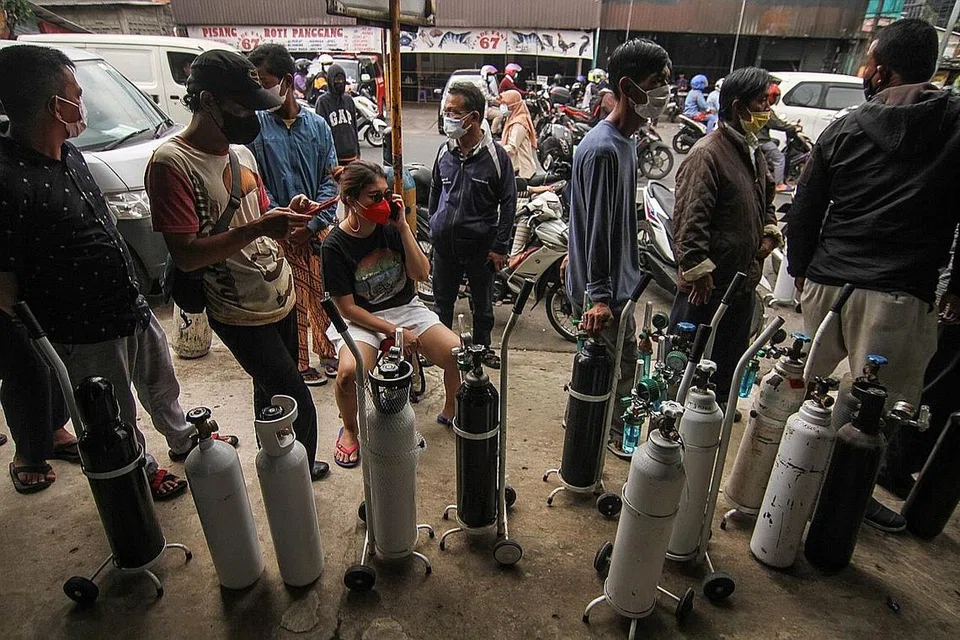 KEPERLUAN OKSIGEN: Orang ramai dilihat menggunakan pelitup beratur bersama tangki oksigen yang perlu diisi semula di luar kedai pembekal oksigen di tengah-tengah lonjakan kes jangkitan Covid-19 di Jakarta. - Foto REUTERS