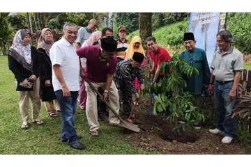 'MENYEMAI' IKATAN ERAT KELUARGA: Encik Hussain Lamat, 'pak lurah' lama keluarga (bersongkok, empat dari kanan) mengetuai acara menanam pokok perpaduan durian belanda dengan dibantu Dr Faishal (tiga dari kanan) dan Encik Mohd Amin Ab Latip, Pengerusi Masjid Petempatan Melayu Sembawang (baris depan, dua dari kiri). Turut hadir ialah anggota keluarga lain, termasuk 'pak lurah' baru, Encik Abdolah (dua dari kanan), dan Encik Suhaimi Salleh (baris depan, kiri), generasi ketiga keluarga itu. - Foto ihsan ABDOLAH LAMAT