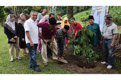 'MENYEMAI' IKATAN ERAT KELUARGA: Encik Hussain Lamat, 'pak lurah' lama keluarga (bersongkok, empat dari kanan) mengetuai acara menanam pokok perpaduan durian belanda dengan dibantu Dr Faishal (tiga dari kanan) dan Encik Mohd Amin Ab Latip, Pengerusi Masjid Petempatan Melayu Sembawang (baris depan, dua dari kiri). Turut hadir ialah anggota keluarga lain, termasuk 'pak lurah' baru, Encik Abdolah (dua dari kanan), dan Encik Suhaimi Salleh (baris depan, kiri), generasi ketiga keluarga itu. - Foto ihsan ABDOLAH LAMAT