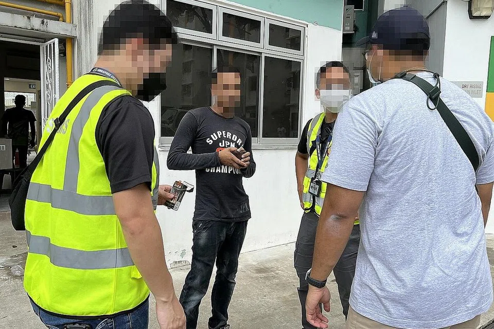 MILIKI ROKOK 'ALIBABA': Pegawai Kastam Singapura berpakaian rompi hijau serta tanpa beruniform menyoal seorang pesalah di sebuah tempat letak kereta di Marine Terrace menemui seorang pekerja migran dari Bangladesh yang didapati menghisap rokok tidak dibayar cukai.