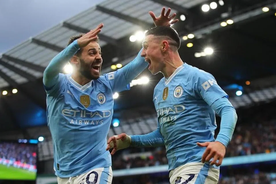 Phil Foden (kanan) dari Manchester City meraikan bersama rakan sepasukan Bernado Silva selepas menjaringkan gol kedua pasukannya menentang Manchester United pada 3 Mac. 